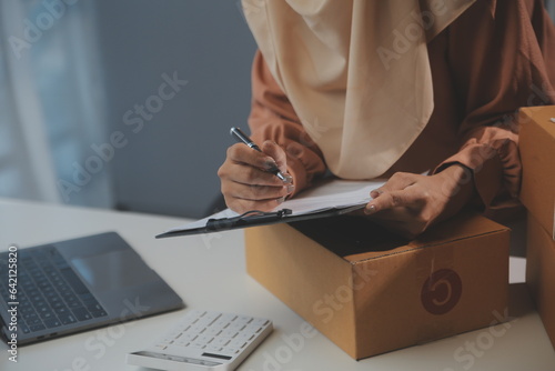 Starting small businesses SME owners female entrepreneurs Write the address on receipt box and check online orders to prepare to pack the boxes, sell to customers, sme business ideas online. photo