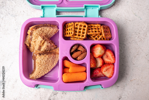фотографія School lunch bento box with carrots, pretzels, strawberries and peanut butter chocolate sandwich