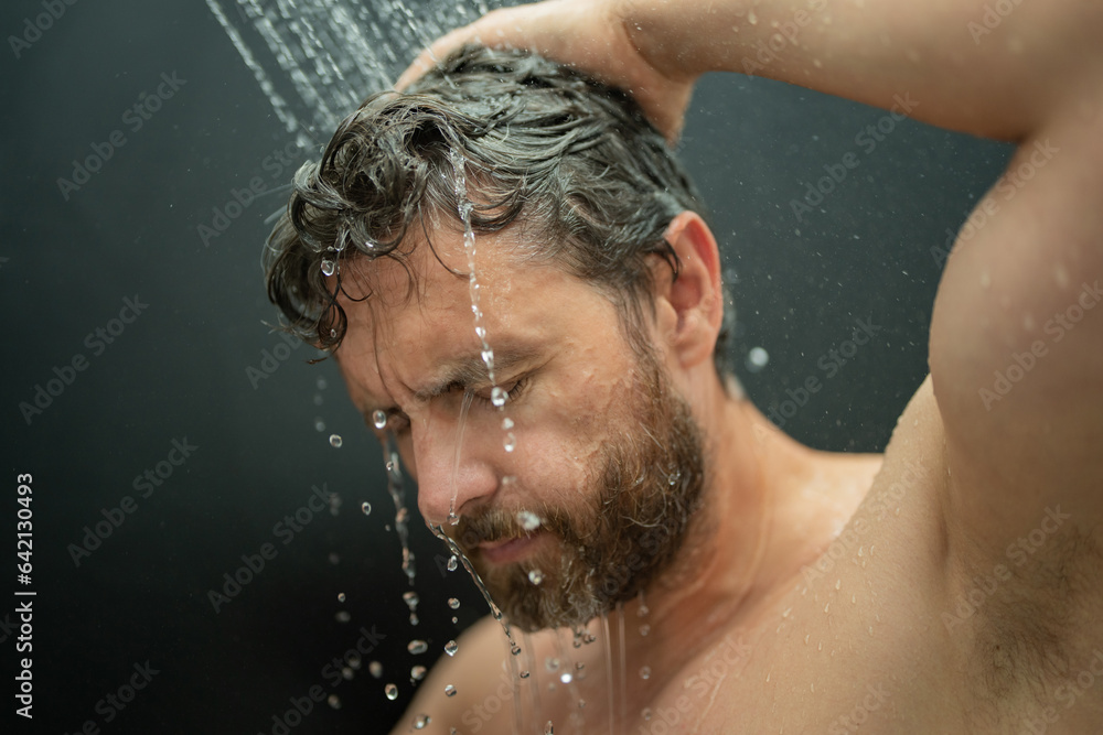 Middle aged man washing hair in bath. Guy bathing shower head in