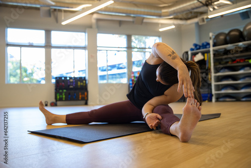 Physically fit woman stretching before exercise in a gym. She is exercising on a yoga mat.  photo