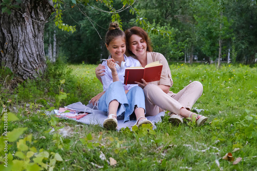 Mom and daughter are sitting on a blanket in the park Mom and daughter are sitting on a blanket in the park