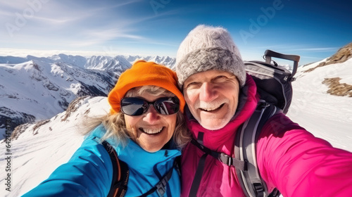 Active senior caucasian couple hiking in mountains with backpacks, enjoying their adventure doing selfie