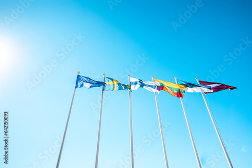 The flags of the Baltic countries and Scandinavia waving in the sky of a beautiful summer day.