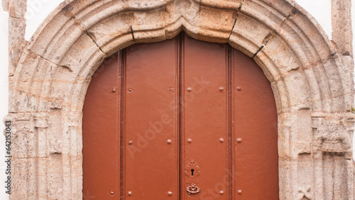 Puerta de madera roja en arco de piedra de iglesia rural