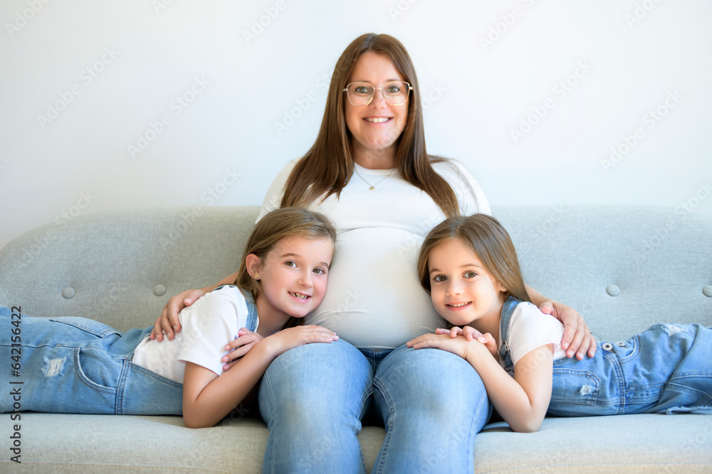 Excited two little daughter with pregnant mom tummy at home Excited two little daughter with pregnant mom tummy at home