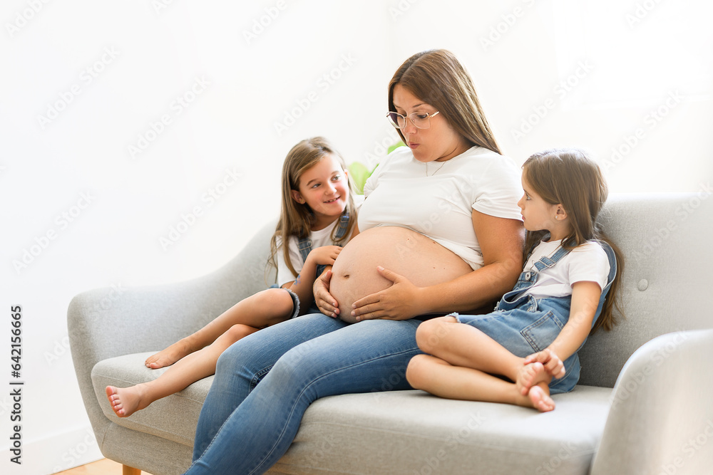 Excited two little daughter with pregnant mom tummy at home Excited two little daughter with pregnant mom tummy at home