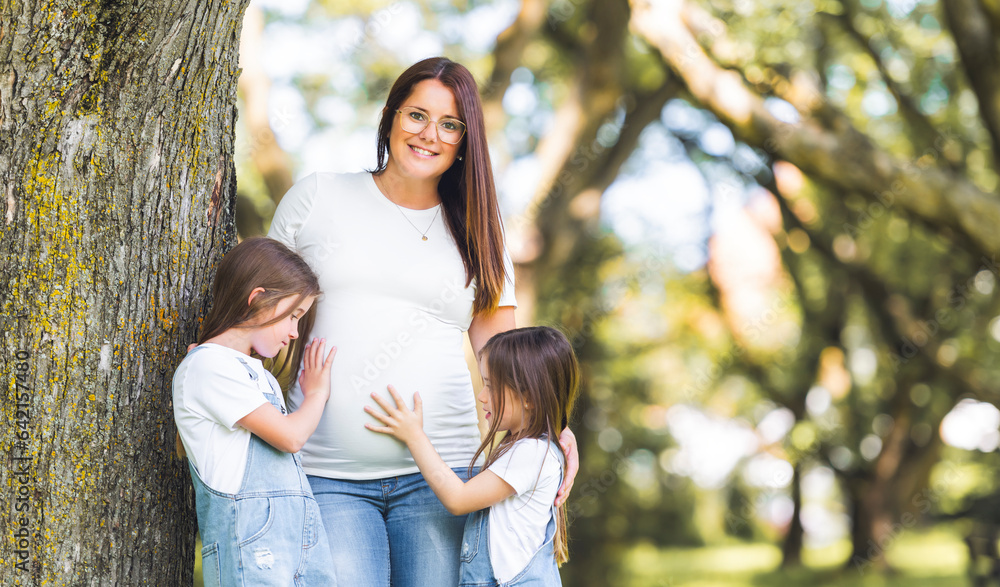 Pregnant woman posing in the parkwith her two childs Pregnant woman posing in the parkwith her two childs