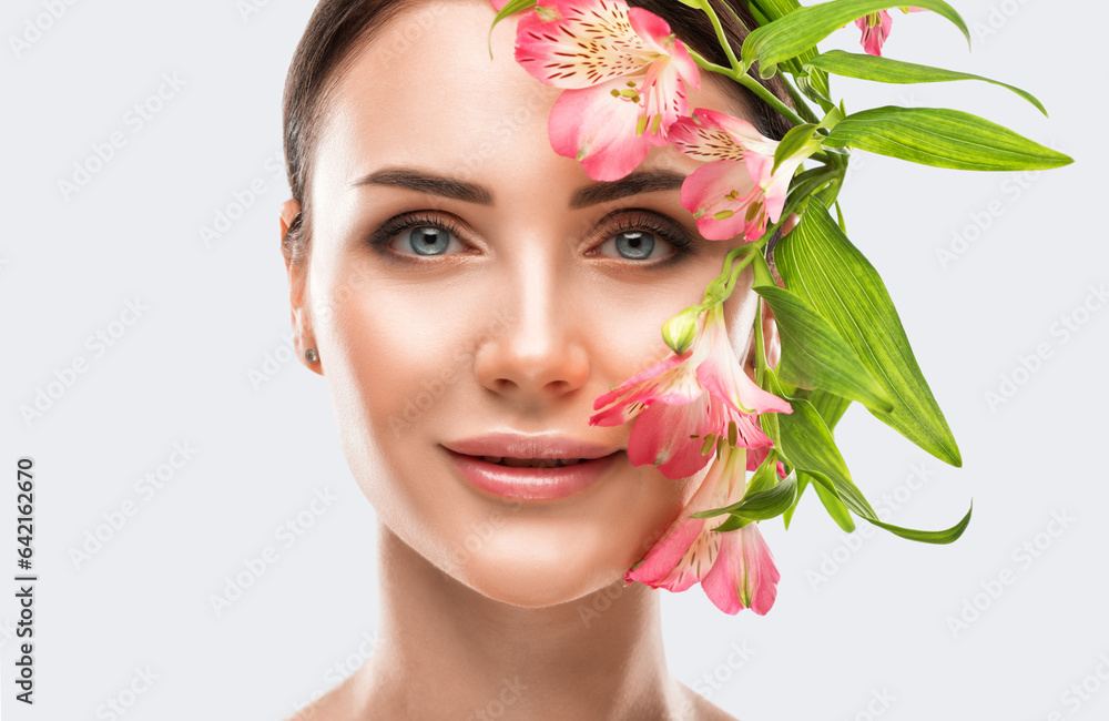 Portrait of attractive girl with healthy clean skin and beautiful make-up. Aesthetic cosmetology and makeup concept.Near her face is a pink flower Portrait of attractive girl with healthy clean skin and beautiful make-up. Aesthetic cosmetology and makeup concept.Near her face is a pink flower