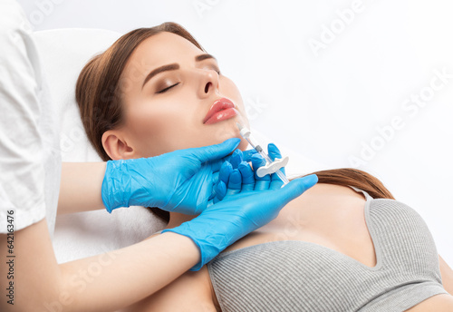 Cosmetologist does injections for lips augmentation and anti wrinkle injections of a beautiful woman. Women's cosmetology in the beauty salon.