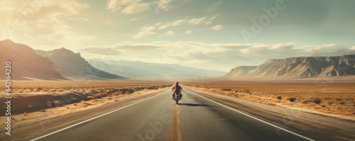 Driver riding motocycle on empty road in sunset light.  Panorama photo.