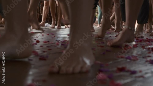 Ecstatic dance, bare feet of dancing people on a wooden floor with flower petals.