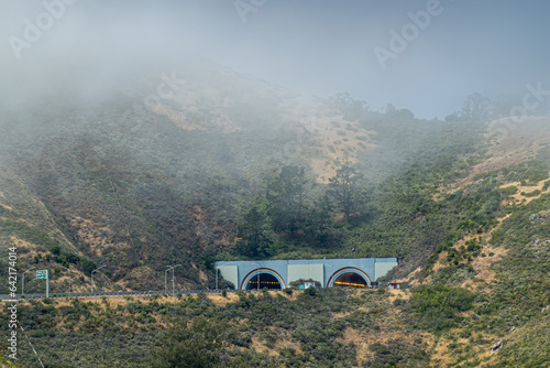 San Francisco, CA, USA - July 12, 2023: South entrance and exit to Robin Williams tunnel across Golden Gate bridge in Marin county. Fog and green hills