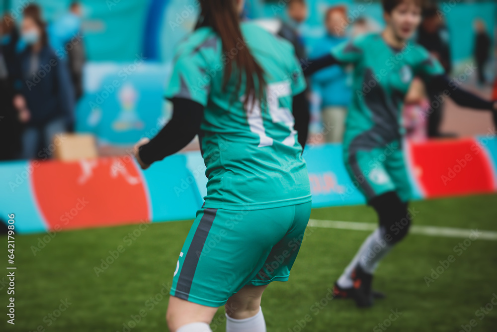 Obraz premium Female football street match outdoor game on an artificial astroturf lawn, girls play soccer game on a pitch field, young women participate in football competition on a stadium with green grass