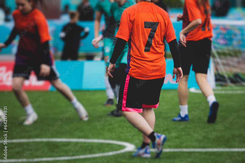 Female football street match outdoor game on an artificial astroturf lawn, girls play soccer game on a pitch field, young women participate in football competition on a stadium with green grass