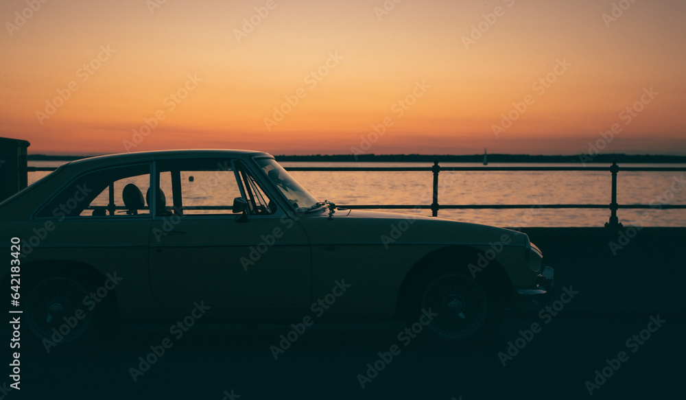 Fototapeta premium A yellow car on the seafront at sunset