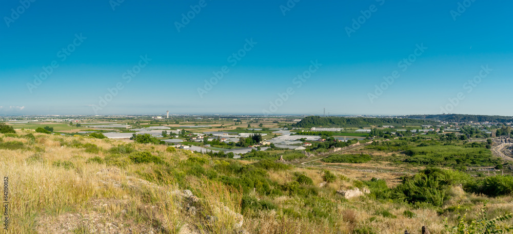 Panorama. Daytime landscape of the surroundings of the ancient city of Perge from a high point. Agricultural fields near the city of Perge in the province of Antalya, Türkiye.