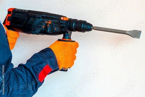 Hands in protective gloves with hammer drill, perforator photo