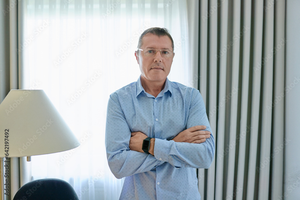 Business mature man in blue shirt looking at camera in office interior Business mature man in blue shirt looking at camera in office interior