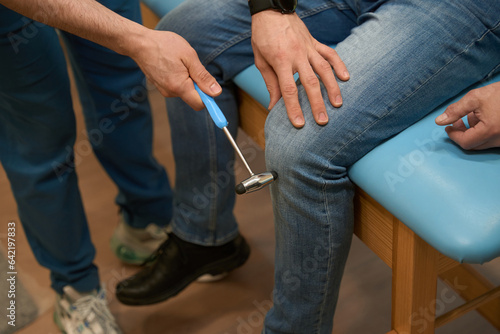 Experienced doctor checking patellar reflex in man during neurological exam