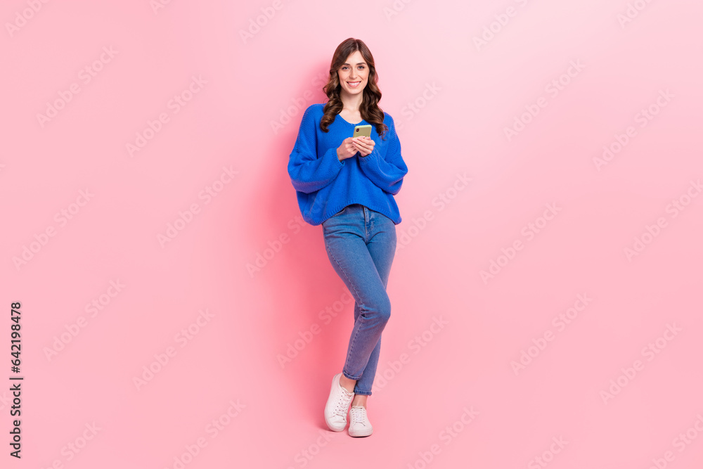 Full size photo of lovely young lady hold device read comments influencer dressed stylish blue garment isolated on pink color background Full size photo of lovely young lady hold device read comments influencer dressed stylish blue garment isolated on pink color background