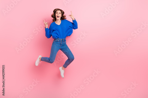 Full length photo of careless person jumping arms fingers demonstrate heavy metal symbol empty space isolated on pink color background