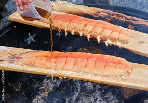 Traditional Indigenous prepartation of salmon filet with maple glaze over open fire