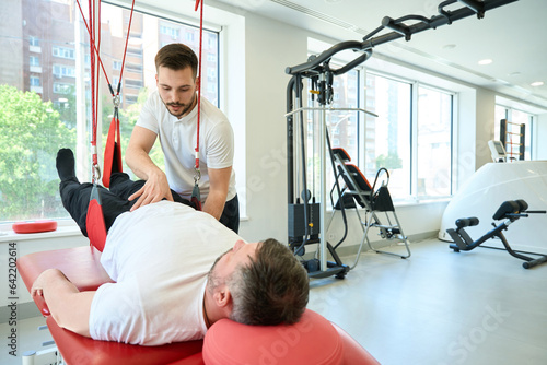 Adult man undergoing physical therapy session on gym equipment