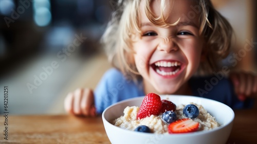 Foto Smiling adorable child having breakfast eating oatmeal porridge with berries