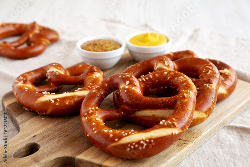 Fotografie, Obraz Homemade Soft Bavarian Pretzels with Mustard on a wooden board, side view