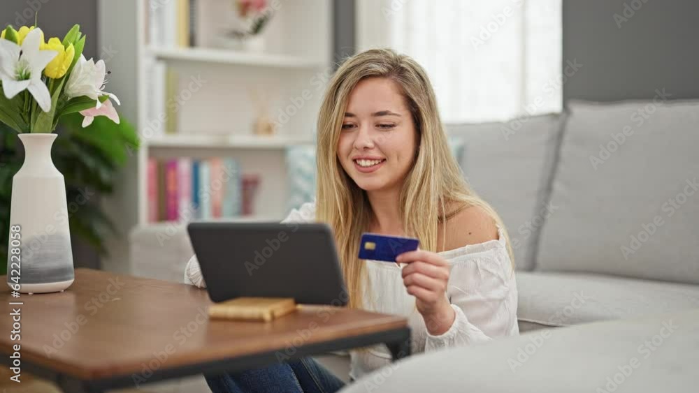 Young blonde woman shopping with touchpad and credit card sitting on floor at home Young blonde woman shopping with touchpad and credit card sitting on floor at home