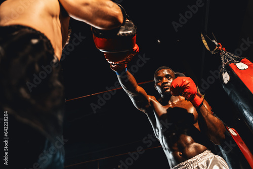 African American Black boxer punching at trainer or coach wearing punching mitts as boxing bag training equipment in the gym. Strength and stamina training for professional boxing match. Impetus © Summit Art Creations