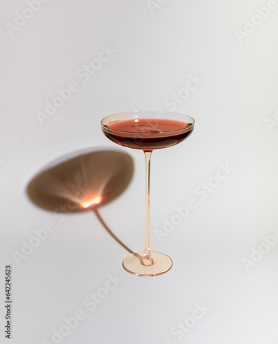 A cocktail glass with red wine sangria on a plain white background with shadow, decorative drink glass