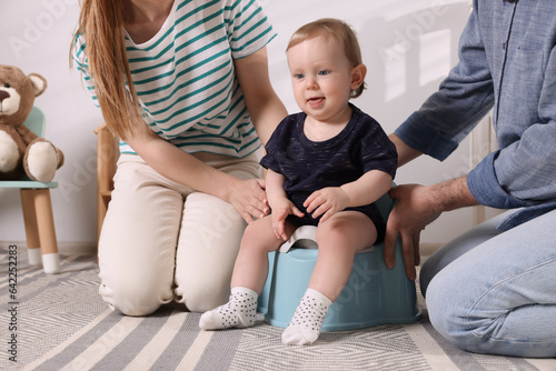 Fotografia Parents training their child to sit on baby potty indoors