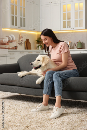 Happy woman with cute Labrador Retriever dog on sofa at home. Adorable pet © New Africa