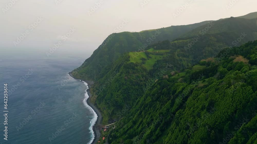 Aerial green seashore mountain on cloudy day. Dark endless ocean washing coast. Aerial green seashore mountain on cloudy day. Dark endless ocean washing coast.