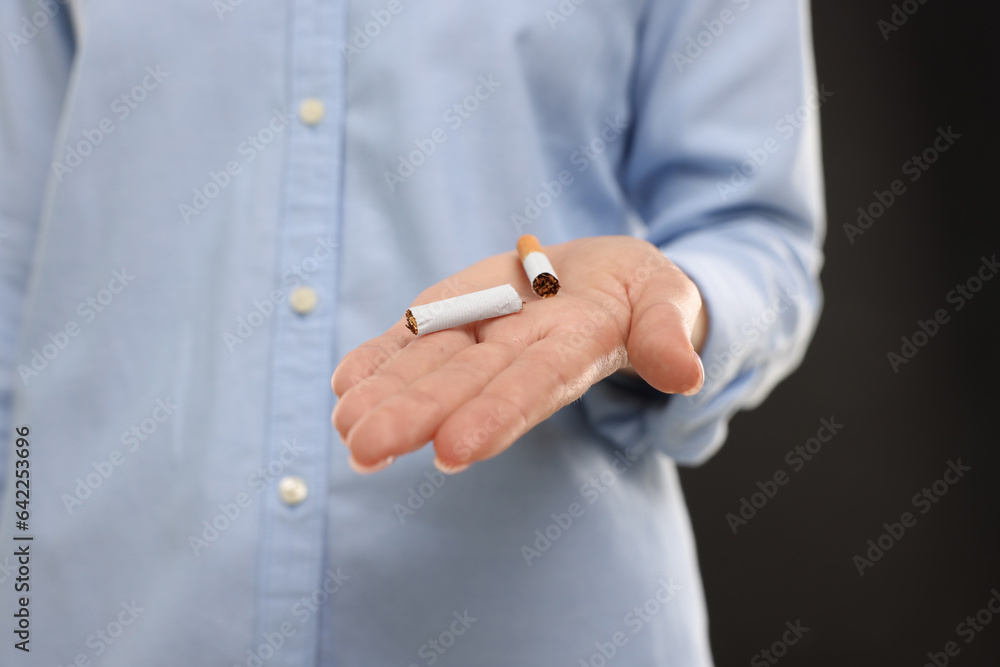 Stop smoking concept. Woman holding broken cigarette on black background, closeup Stop smoking concept. Woman holding broken cigarette on black background, closeup