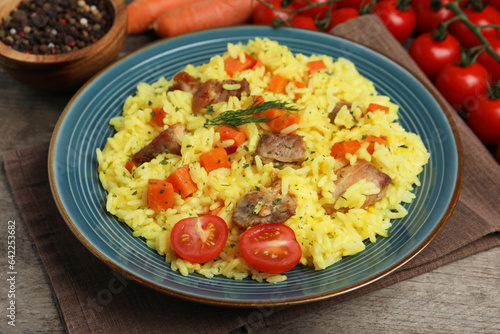 Delicious pilaf with meat and vegetables on wooden table, closeup