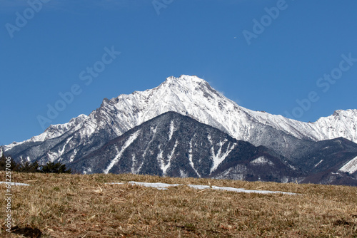 牧草地越しに望む雪を頂いた赤岳