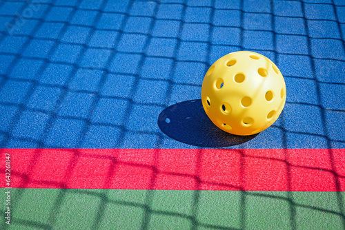 Yellow Pickleball on a Pickleball court.