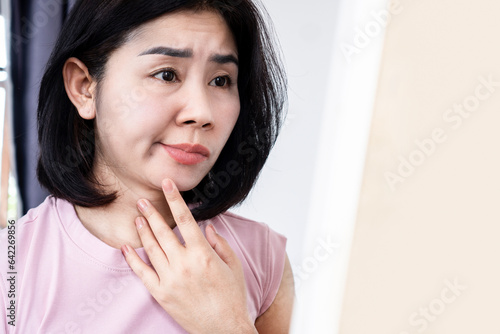 Asian woman having problem with Bell's Palsy,Facial Palsy, hand holding her face in front of a mirror photo