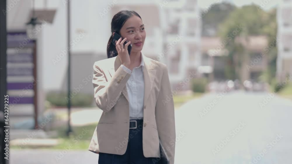 beauty young Asian successful businesswoman or freelance wearing suit standing on outside office talking on smart mobile phone for her job beauty young Asian successful businesswoman or freelance wearing suit standing on outside office talking on smart mobile phone for her job
