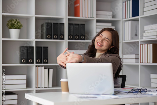 Business women or working lady are stretch oneself or lazily for relaxation on her desk while doing her work in the office. photo