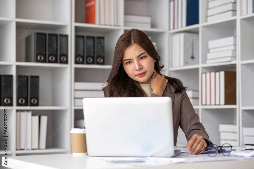Young Asian businesswoman working on laptop computer, stressed has a headache and thinks hard from work at the office. Young Asian businesswoman working on laptop computer, stressed has a headache and thinks hard from work at the office.