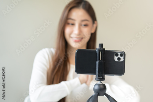 Vlogger influencer, attractive asian young woman blogger, content maker looking at camera, recording interview on smartphone, talk on video shoot social media, live broadcast with technology at home.