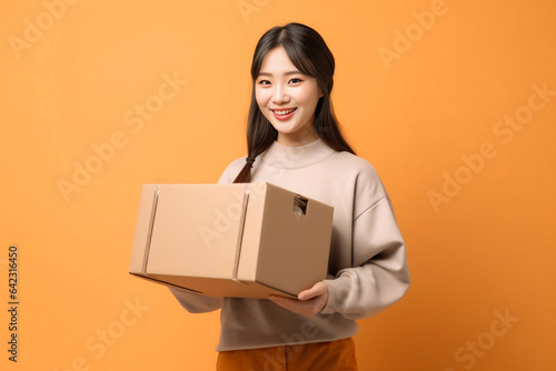Asian woman prepares a package for online shopping delivery, while a cheerful delivery woman in an orange uniform stands with a parcel post box. Generative AI.