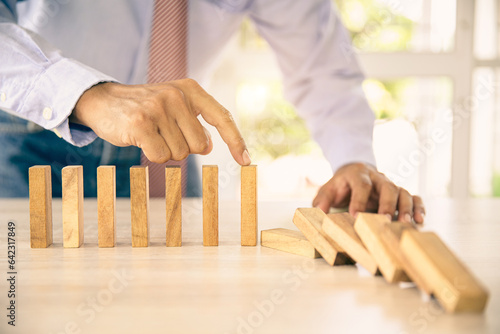 Close-up hand prevent wooden block not falling domino concepts of financial risk management and strategic planning and business challenge plan or safety insurance.