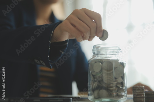 saving money and accounting concept. business man putting coin insert to jar and make acounting book for finance management to investment and saving. photo