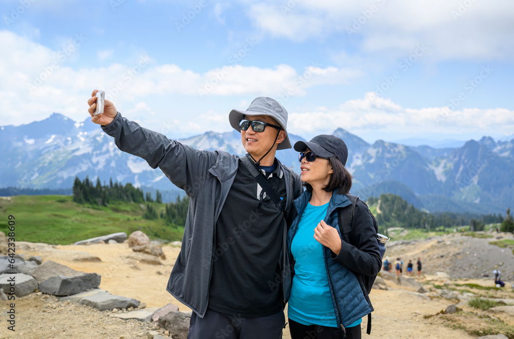 Couple taking selfie photo using smartphone at Skyline Loop Trail. Mt Rainier National Park. Washington State