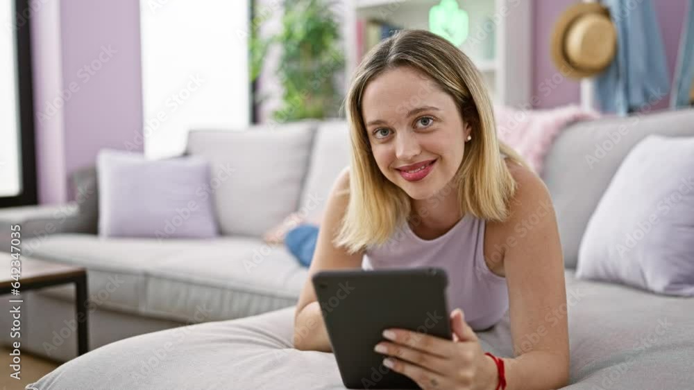 Young blonde woman using touchpad lying on sofa at home Young blonde woman using touchpad lying on sofa at home