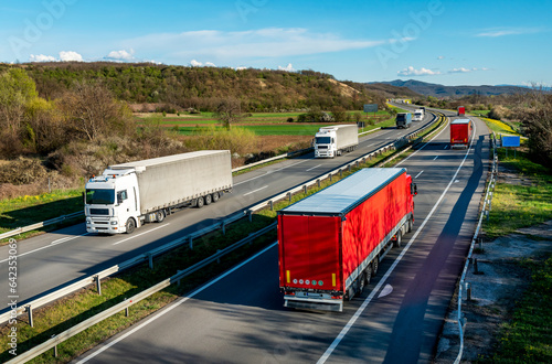 Heavy Highway transportation scene with Convoys or fleets of transportation trucks in both ways,on rural highway under a beautiful blue sky photo